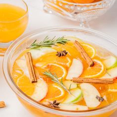 a glass bowl filled with orange slices and cinnamon stick garnished with an apple slice