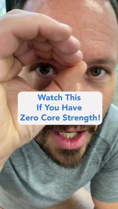 a man holding up a sign that says watch this if you have zero core strength