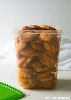 a plastic container filled with fried food sitting on top of a table next to a green spatula