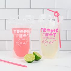 two plastic cups with straws and lime slices next to each other