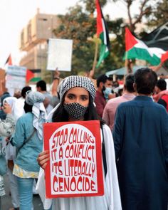 a woman holding a sign that reads stop calling it a conflict, its literally genocie