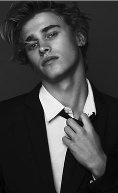 black and white photograph of a young man adjusting his tie