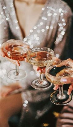 three people holding up wine glasses in their hands