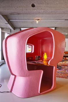 an unusual pink desk in the shape of a chair with a yellow light on it