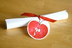 an apple shaped ornament on top of a white paper towel with red ribbon