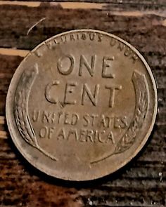 an old one cent coin sitting on top of a wooden bench with the words, united states of america