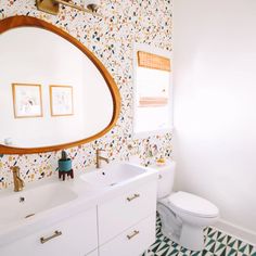 a bathroom with a white toilet and a large round mirror above it's sink