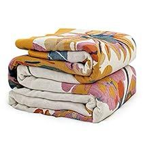 three folded blankets stacked on top of each other in different colors and patterns, with one folded up to the side