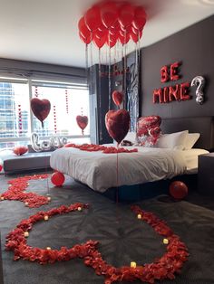 a bedroom decorated with red balloons and streamers in the shape of heart - shaped hearts