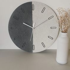 a clock sitting next to a vase with dried flowers