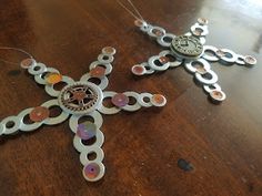 two metal ornaments on a wooden table with one being cut out to look like a cross