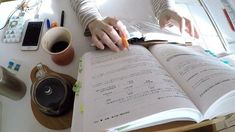 a person sitting at a desk with an open book and coffee cup on the table