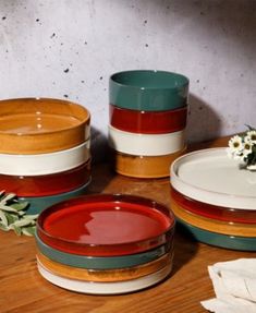 a table topped with plates and bowls on top of a wooden table next to a plant