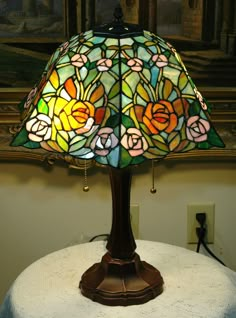 a stained glass lamp sitting on top of a table next to a wall mounted painting