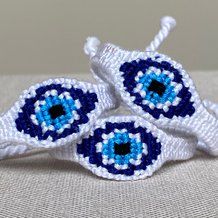 two blue and white eyeballs are sitting on top of each other, one is made out of yarn