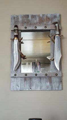 a mirror mounted to the side of a wall with two knives hanging from it's sides