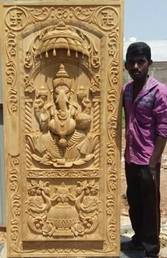 a man standing next to a carved wooden ganesha panel with an elephant on it