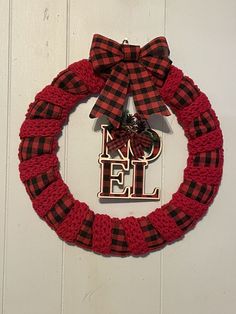 a red and black wreath hanging on the side of a wall with a monogrammed letter