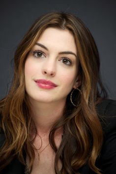 a woman with long brown hair wearing a black blazer and silver shirt is looking at the camera