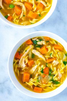 two bowls of chicken noodle soup with carrots and parsley