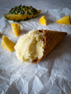 an ice cream cone with pineapple and coconut sorbet in it on white paper