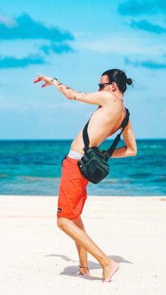 a man on the beach throwing a frisbee in the air with one hand