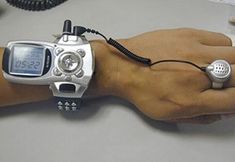 a person's wrist with a watch on it and a cell phone attached to the wrist