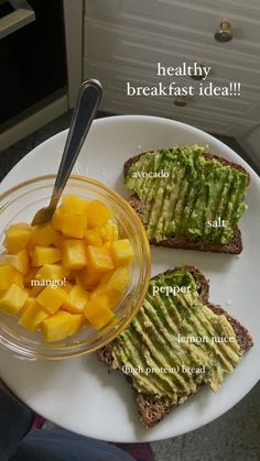 a plate with toast, avocado and mango slices on it next to a bowl of fruit