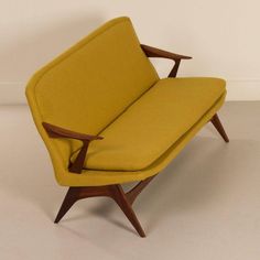 a yellow chair sitting on top of a white floor next to a wooden framed wall