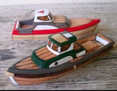 two wooden toy boats sitting on top of a wooden table next to eachother