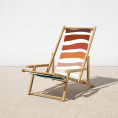 a wooden lawn chair sitting on top of a cement floor next to a white wall