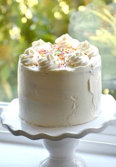 a white cake with sprinkles sitting on top of a window sill