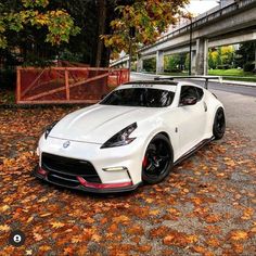 a white sports car parked on the side of a road in front of a bridge