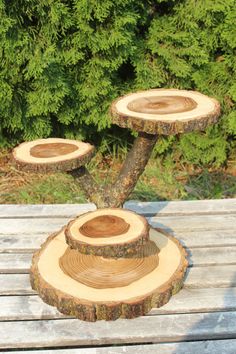 three wood slices stacked on top of each other in front of some bushes and trees