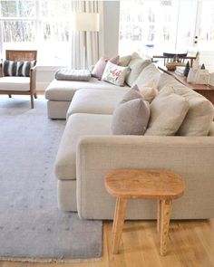 a living room filled with furniture and a wooden table in front of a large window