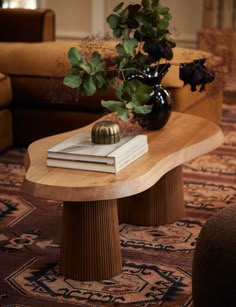 a table with books and a vase on it in front of a couch or chair