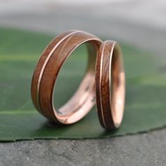 two gold wedding rings sitting on top of a green leaf