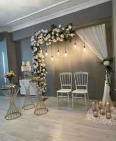 a room with white chairs and flowers on the wall