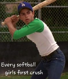 a young man holding a baseball bat on top of a field