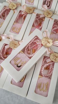 some pink and white boxes with gold foiled letters, bows and pearls on them