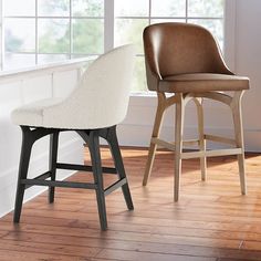 two chairs sitting next to each other on top of a hard wood floor in front of a window