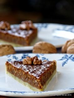 there is a piece of pie on the plate with walnuts around it and another slice in the background