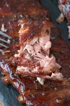 bbq ribs with barbecue sauce and a fork in the middle on a black plate