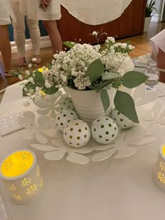 a vase filled with white flowers sitting on top of a table next to two candles