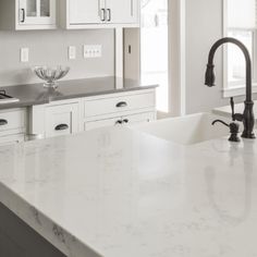 a large kitchen with white cabinets and marble counter tops is seen in this image from the front view