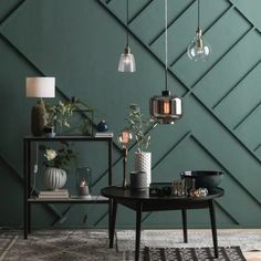 a living room with green walls and two tables on the floor, one is black