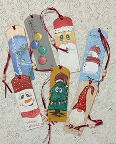 four christmas bookmarks with santa claus, snowman and penguin on them hanging from red string