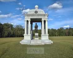 a monument in the middle of a field with a statue on it's pedestal