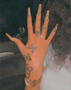 a woman's hand with tattoos and rings on it, sitting in a car