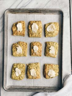 nine cookies with white icing on a baking sheet